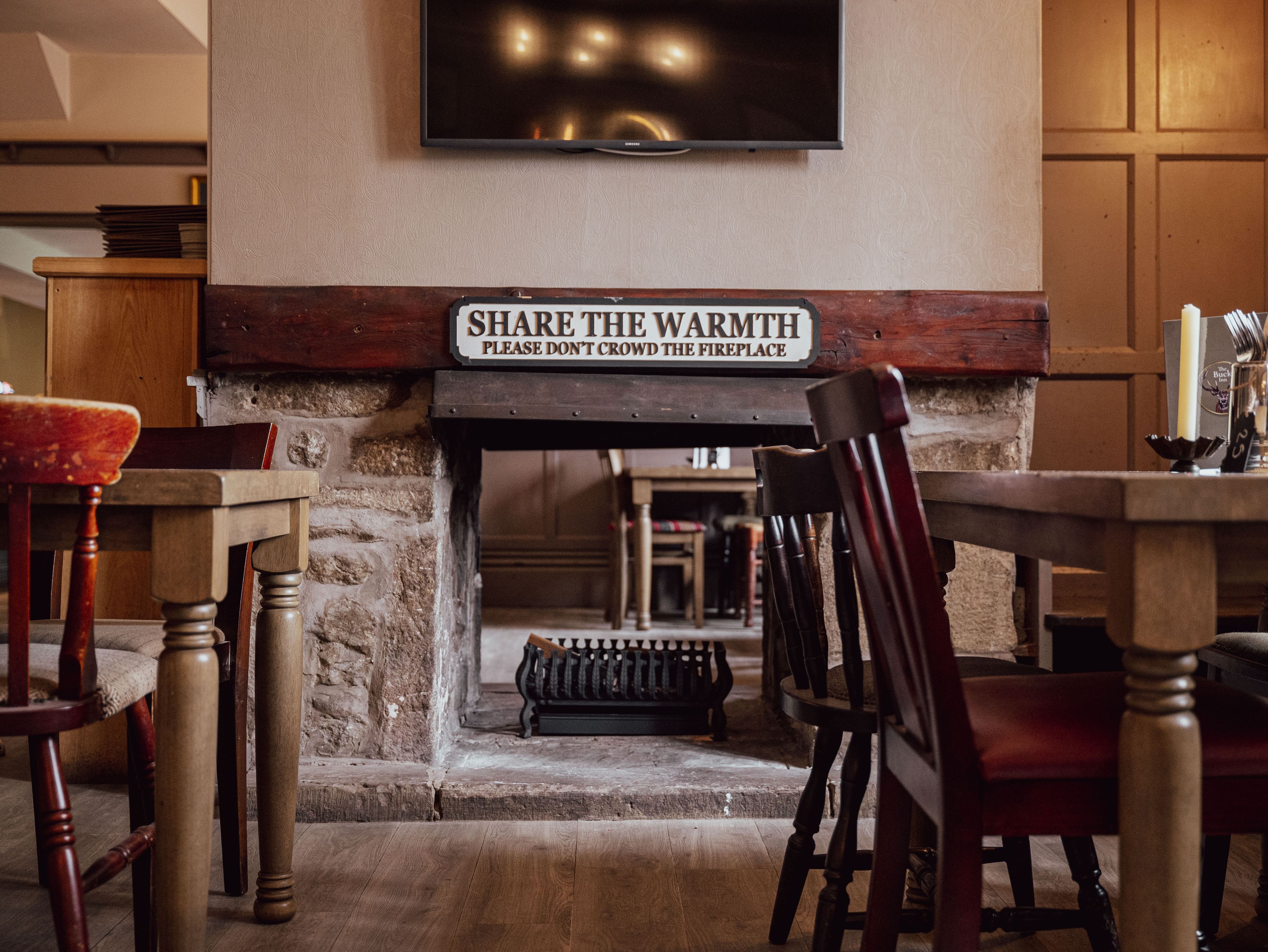 fireplace in the restaurant area with sign 'share the warmth'