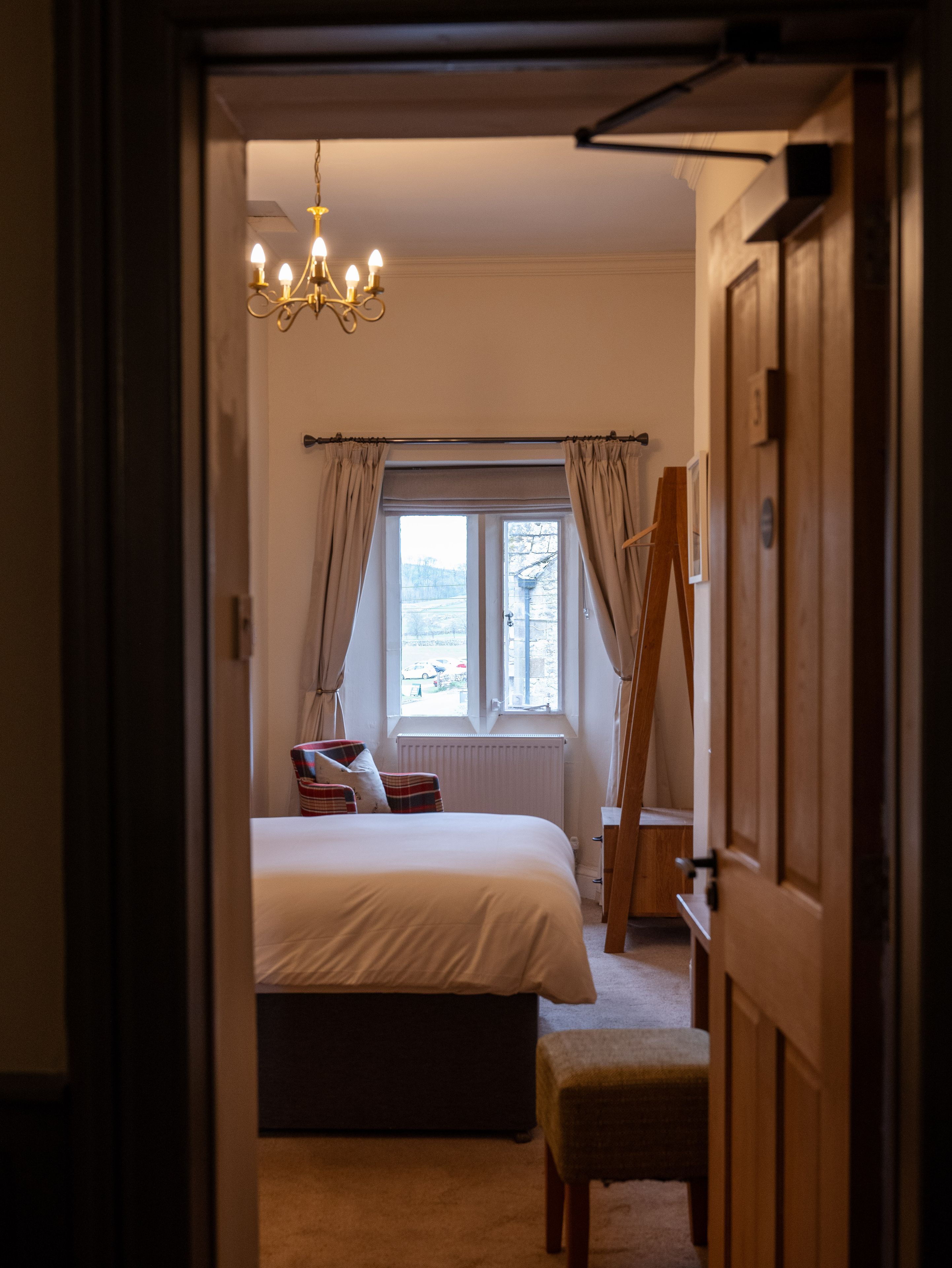 cosy bedroom through the doorway with chair by the window